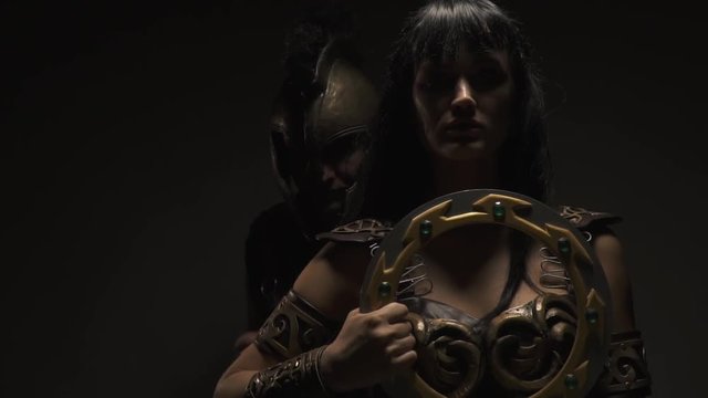 Pathos Amazon stands with a battle disk, the Roman legionary approaches her and lies on the shoulder