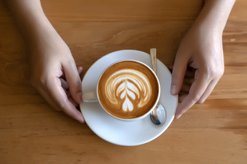 women  Holding coffee cup, wooden table  cafe while having coffee