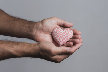 Male hands holding a cloth heart. Blood donation concept.