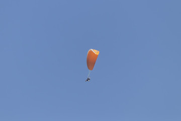Paraglider flying with a paramotor over clear blue sky