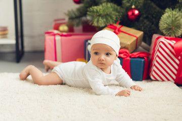 Obraz na płótnie Canvas beautiful little baby lying on floor with christmas gifts
