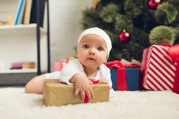 Fototapeta na wymiar adorable little baby lying on floor with christmas gifts