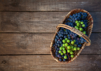 basket with grapes on wooden surface