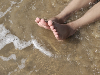 summer, beach, leisure and body part concept - closeup of human feet on the beach