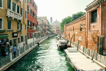 Venice, Italy. Quay of a water channel with moored cargo boats. Along the canal there are bright Venetian houses.