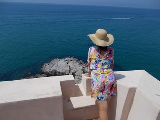 Kobieta w słomkowym kapeluszu na tle turkusowego morza. Italia