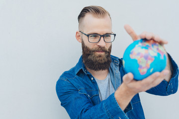 junger mann mit bart schaut auf den globus