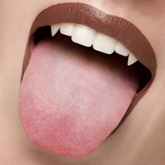 Obraz premium Macro photo of sexy female lips with natural scarlet lipstick. Woman shows her tongue and snow-white teeth with fangs like a vampire. Dentistry, cosmetology, halloween