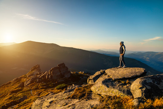 Young man on top of a mountain watching the sunset
