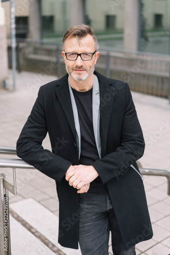 Street portrait of mature man wearing black coat