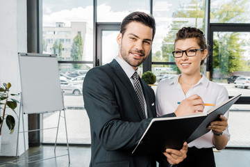 portrait of smiling businessman signing papers with colleague near by  in office