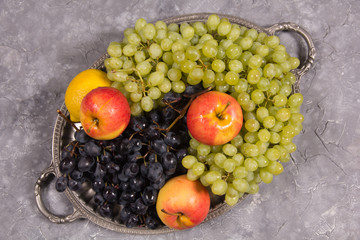 Dark and light grapes, apples lie on an old tray