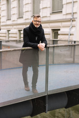 Stylish middle-aged man standing on a bridge