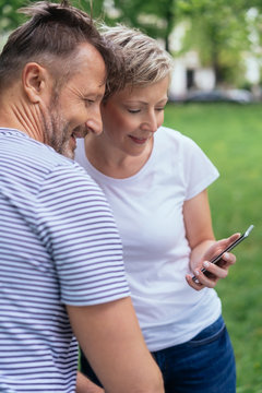 Couple in a park looking at a message on a mobile