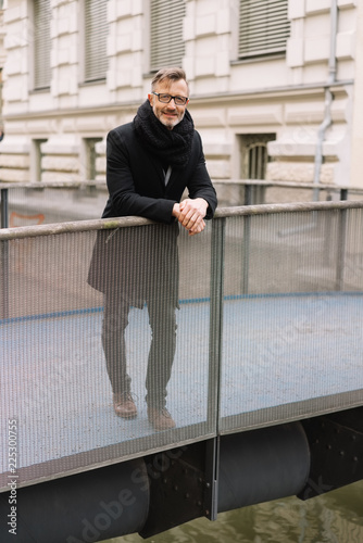 Stylish middle-aged man standing on a bridge