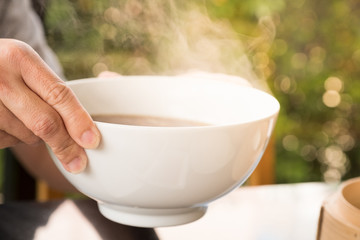 Hot soup and smoke in white bowl.