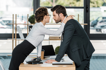 side view of businessman and businesswoman flirting at workplace in office