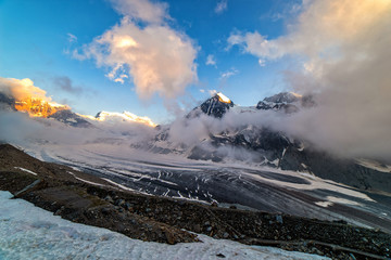 Obraz premium Dramatic sunset scene in high mountains. Clouds covering high peaks of Valais Alps (Pennine Alps), Switzerland in a evening light.