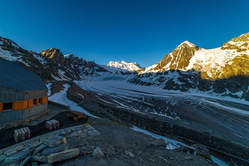 Obraz premium Scenic view of beautiful landscape of Swiss Alps with a majestic Glacier de Corbassiere in a view, Switzerland. Clear sky sunrise in Valais Alps (Pennine Alps), Switzerland in a early morning light.