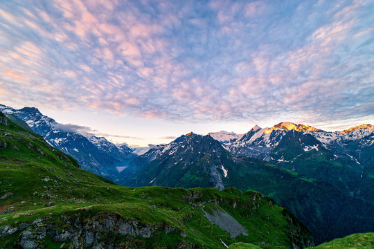 Scenic view of beautiful Swiss Alps mountains. Dramatic early morning scene in high mountains with first light. Blue hour sunrise with pink and blue tones, Switzerland.