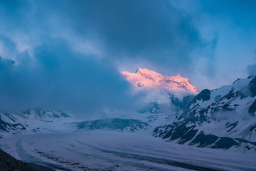 Obraz premium Glacier de Corbassiere, Switzerland. Dramatic sunset scene in high mountains. Clouds covering high peaks of Valais Alps (Pennine Alps), Switzerland in a evening light.