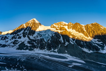 Obraz premium Scenic view of beautiful landscape of Swiss Alps with a majestic Glacier de Corbassiere in a view, Switzerland. Clear sky sunrise in Valais Alps (Pennine Alps.
