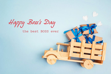Boss day greeting card with wooden toy truck and gift box in the back on blue background.