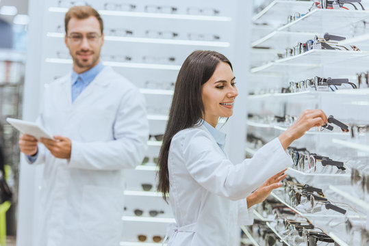 two optometrists working and using digital tablet in ophthalmic shop with eyeglasses