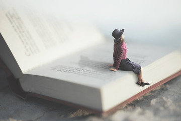 surreal moment of a woman relaxes sitting on a giant book - obrazy, fototapety, plakaty