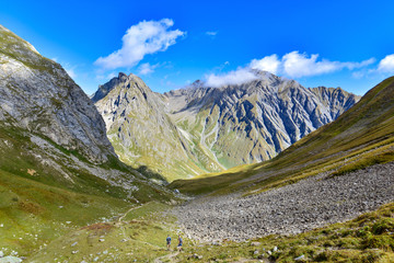 large view on peeks mountains and two hikers walking in the valley