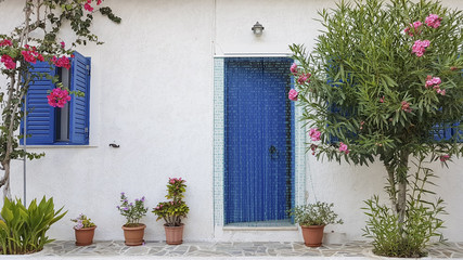 Tradycyjny grecki bialy budynek dom z niebieskimi oknami i drzwiami i oleander - obrazy, fototapety, plakaty