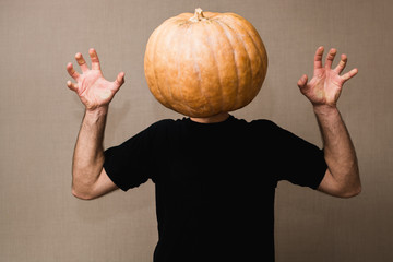 Young man in black t-shirt with a big pumpkin instead of his face