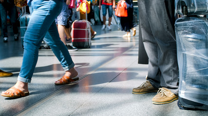 Out of focus photo of passenger's feet and bags on floor at international airport terminal
