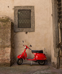 Red scooter parked in a side street in Siena, Tuscany