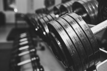Obraz na płótnie Canvas Heavy dumbbells lying in the raw in the gym. Fitness sport motivation. Happy healthy lifestyle living. Exercises with bars weights.