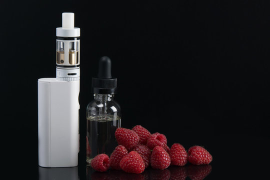 above the black mirror background is a white electronic cigarette, raspberries, and a bottle of dressing for her.