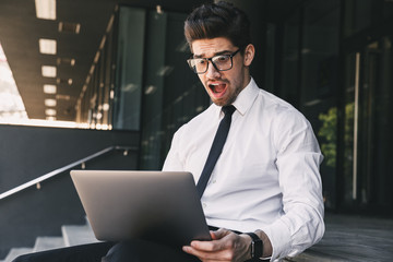 Shocked business man near business center using laptop computer.