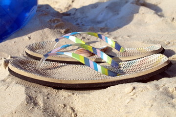 Multicolored flip-flops on a sandy beach