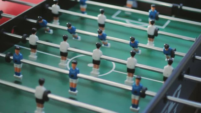 Friends having fun together playing foosball. Colleagues playing table football on break. Office people enjoying table soccer game. Close up of table football kicker game