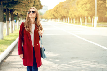 Obraz premium Beautiful woman female bag coat sweater jeans smile watch sunglasses in the street sun