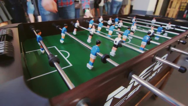 Teenagers playing table football. Young office people enjoying table soccer game. Close up of table football kicker game