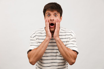 Shocked handsome man standing isolated over white background wall.