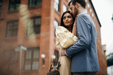 Love story in New York. Gorgeous couple of American man with beard and tender Eastern woman hug...