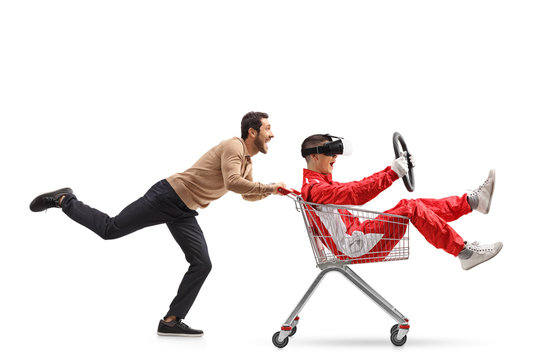 Teenager in a racing suit with VR googles in a shopping cart being pushed by a young man