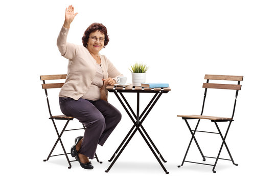Senior lady sitting at a coffee table and waving