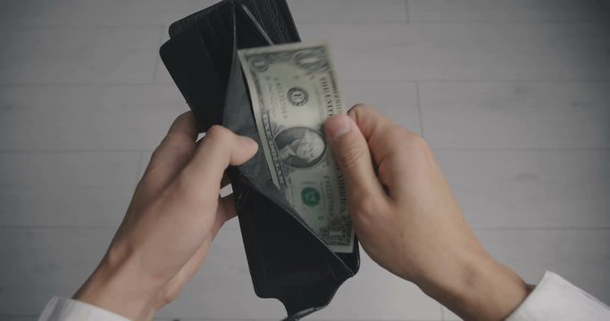 Close-up of a man's hand holding Leather Wallet Empty with one dollar banknote. The concept of lack of money. Lack of funds