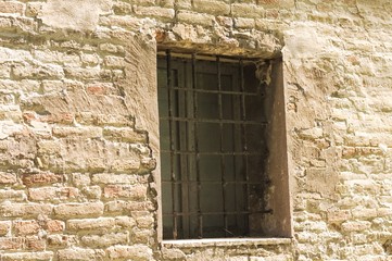 Isolated medieval window with iron gratings (Marche, Italy, Europe)