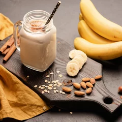 Bananenprotein-Smoothie oder Milchshake mit Hafer, Mandelmilch auf Holzbrett. Quadratischer Zuschnitt, selektiver Fokus
