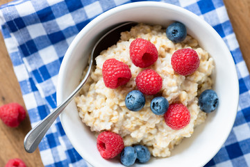 Oatmeal porridge bowl with berries on checkered napkin, top view. Healthy eating, nutrition, healthy lifestyle concept