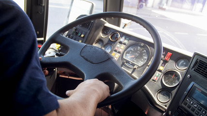 Closeup image of driver holding hands on truck steering wheel